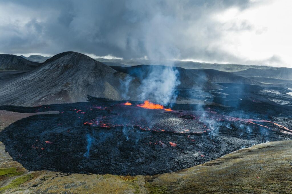 Aerial view of an active volcano erupting with lava in Iceland's rugged landscape.