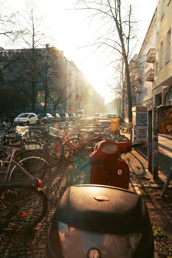 Sunlight streams down a street lined with parked bicycles.